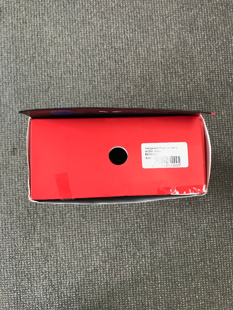 A red shoebox shown from a top-down view on a gray textured carpet. The box has a white barcode label on the right side and a circular cutout in the center.